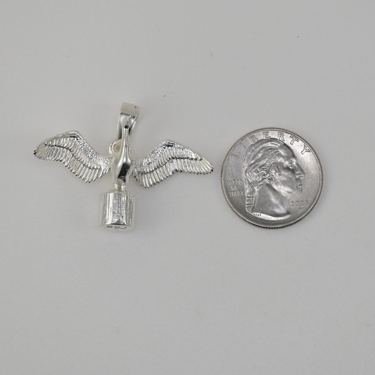 Cormorant pendant in sterling silver size reference next to a quarter