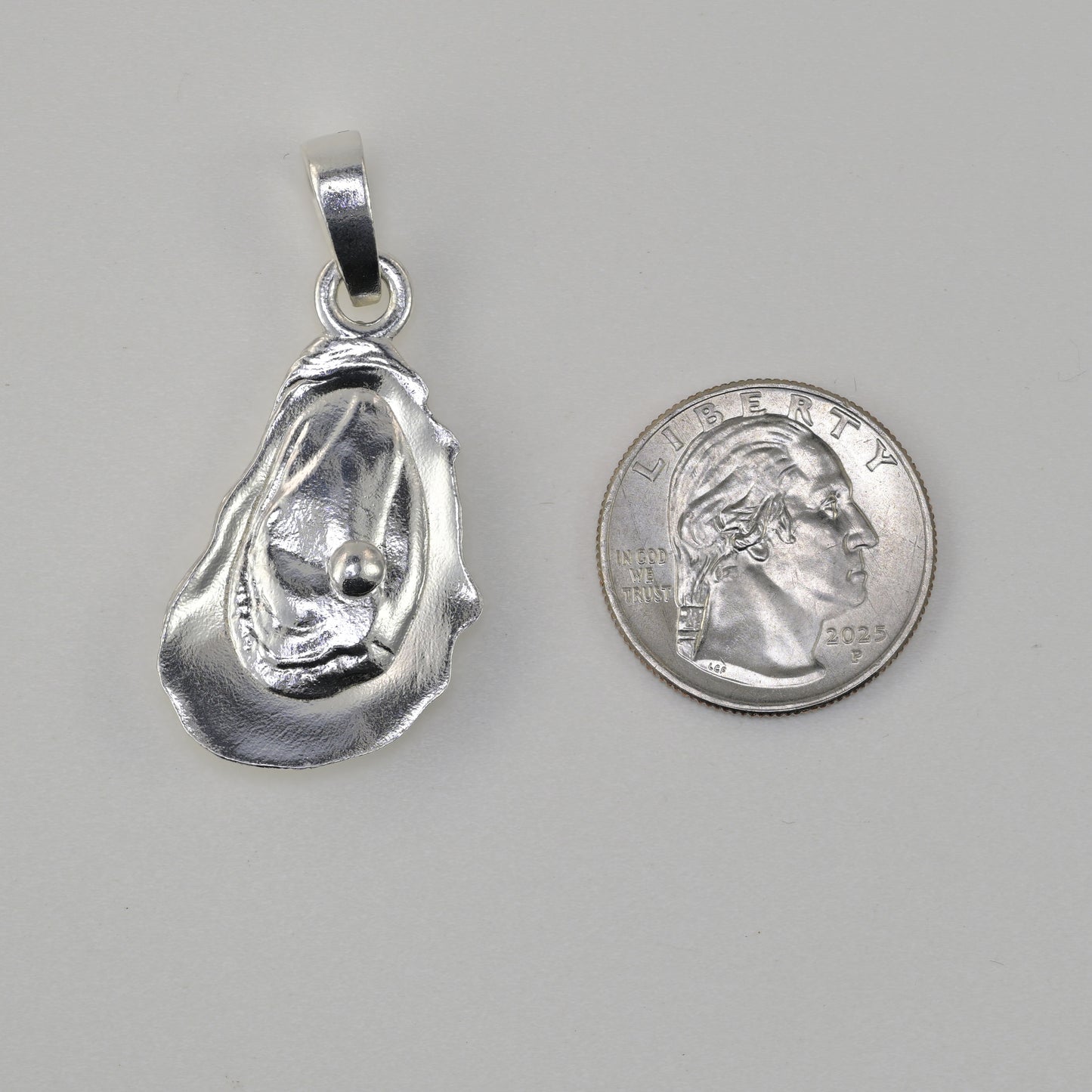 Oyster pendant size reference next to a quarter