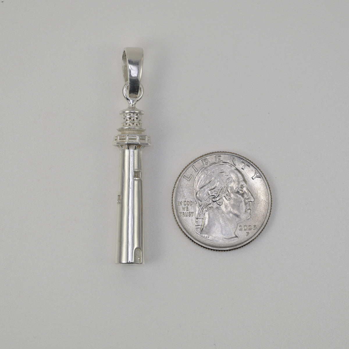 Lighthouse made in solid sterling silver size referenced next to a quarter